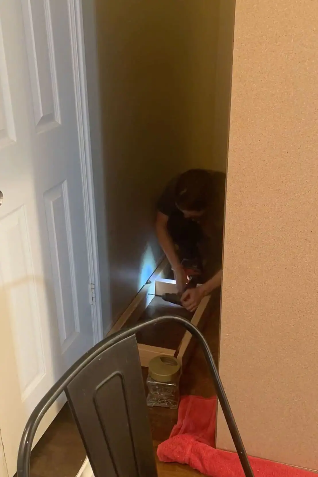 Securing the wooden support frame in a narrow space, prepping for the next phase of the DIY built-in storage project.